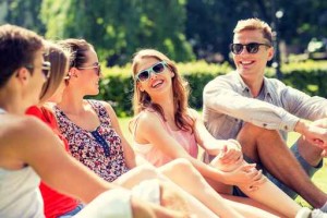 group of smiling friends outdoors sitting in park