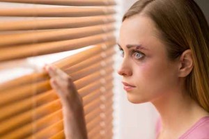 Scared woman is looking through the window.