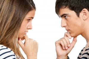 Close up portrait of teen couple looking at each other with wondering expression.Isolated on white.