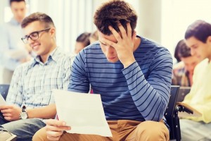 education, high school, teamwork and people concept - student with paper and pen sitting with group of classmates